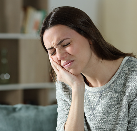 A woman holding her cheek due to a toothache.